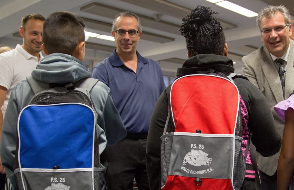 From left, Realtors Kevin Swetsky and Mike Gentilesco work with Assistant Principal Anthony Casella in distributing SIBOR Pack To School supplies in 2015 to students at PS 25/South Richmond High School, Pleasant Plains.